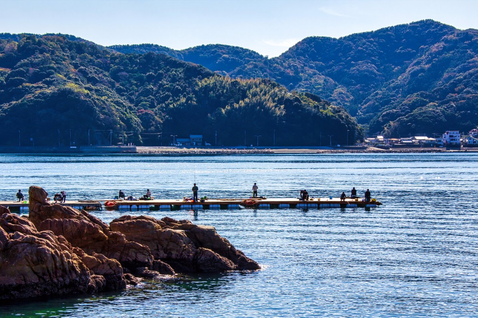 夕焼けの海釣り公園で釣りを楽しむ若い友だちグループ