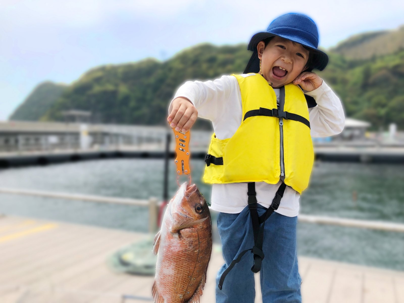 海上釣り堀のイカダでタモを持って笑う子どもたち